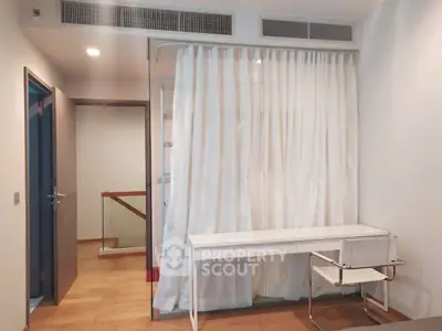 Modern study area with sleek desk and chair, featuring elegant curtains and wooden flooring.