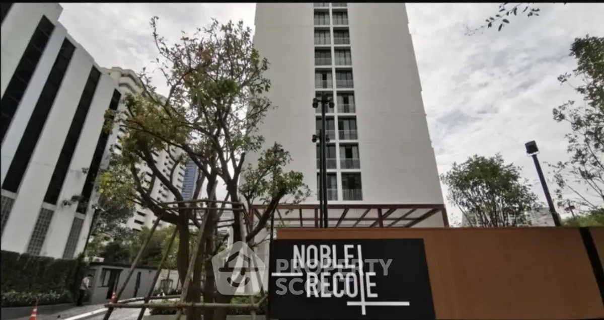 Modern high-rise building with lush greenery and stylish signage