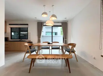 Modern dining area with wooden table and chairs, open layout kitchen, and large window view.