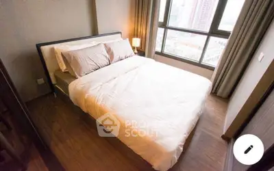 Cozy bedroom with large windows and wooden flooring in a modern apartment.