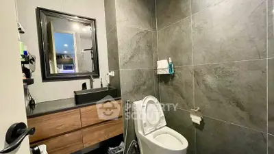 Modern bathroom with sleek fixtures and elegant dark tiles.