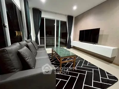 Modern living room with sleek furniture and large TV, featuring a stylish geometric rug and floor-to-ceiling windows.