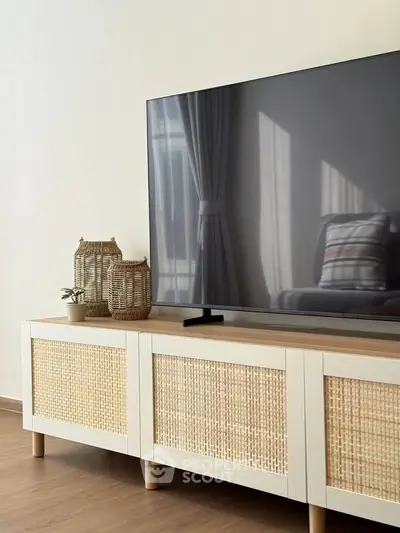 Modern living room with stylish TV stand and large flat-screen TV, featuring natural light and elegant decor.