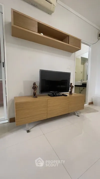 Modern living room with sleek TV stand and wall-mounted shelf, showcasing minimalist decor.