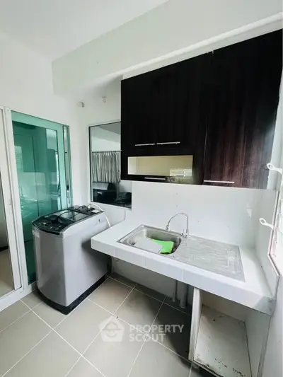 Modern laundry area with washing machine and sleek cabinetry in a bright, tiled space.