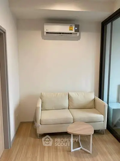 Modern living room with beige sofa, wooden floor, and air conditioning unit.