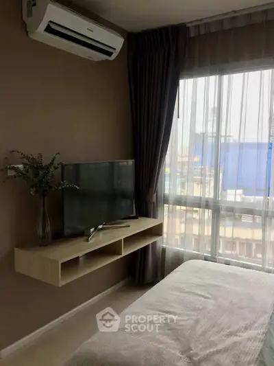 Cozy bedroom with modern TV setup and large window view