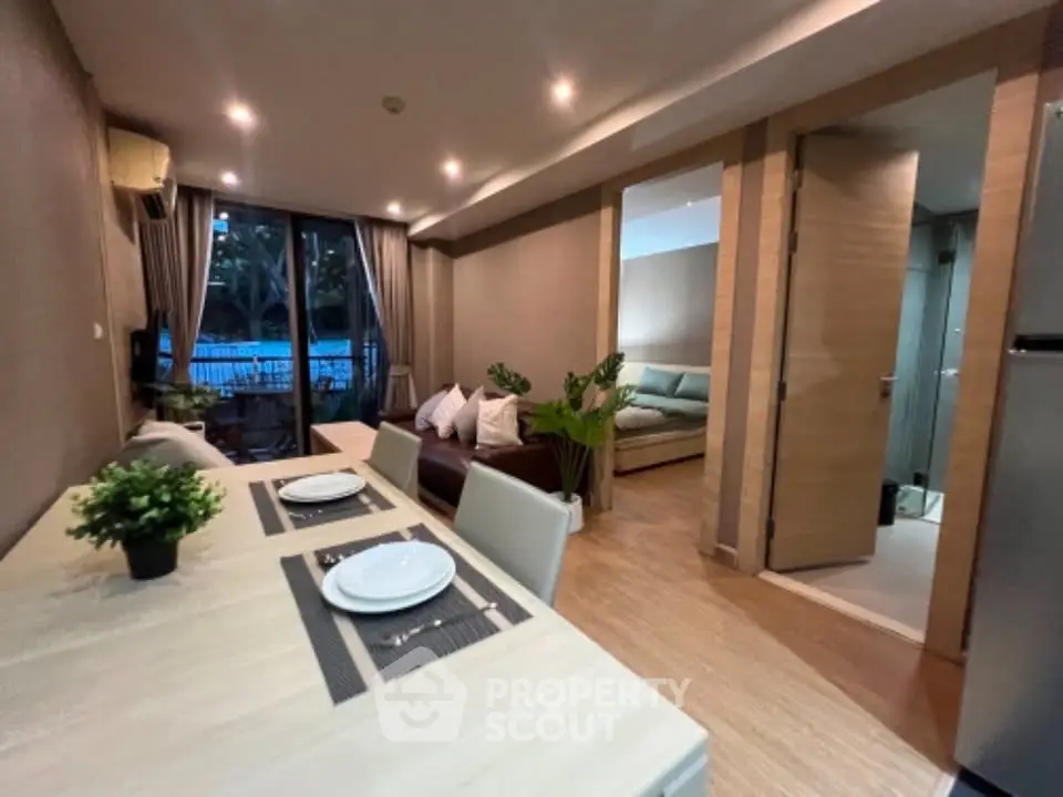 Modern open-plan living room with dining area and view of bedroom, featuring stylish decor and pool view.