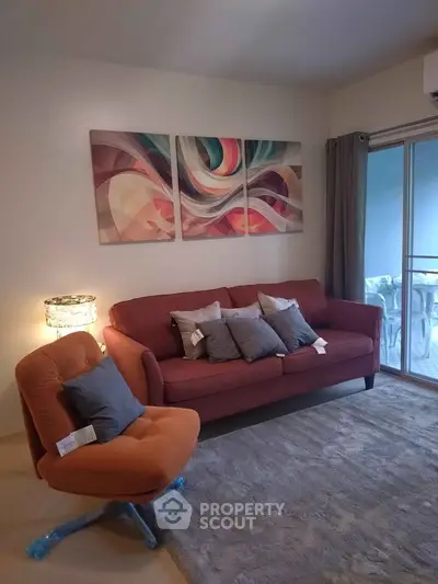 Cozy living room with modern art, plush seating, and natural light from balcony.