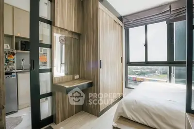 Modern bedroom with large window and built-in wardrobe offering natural light and city view.