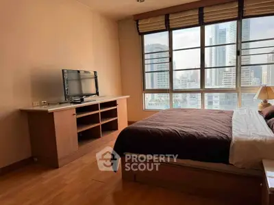 Spacious bedroom with city view and modern furnishings in a high-rise apartment.