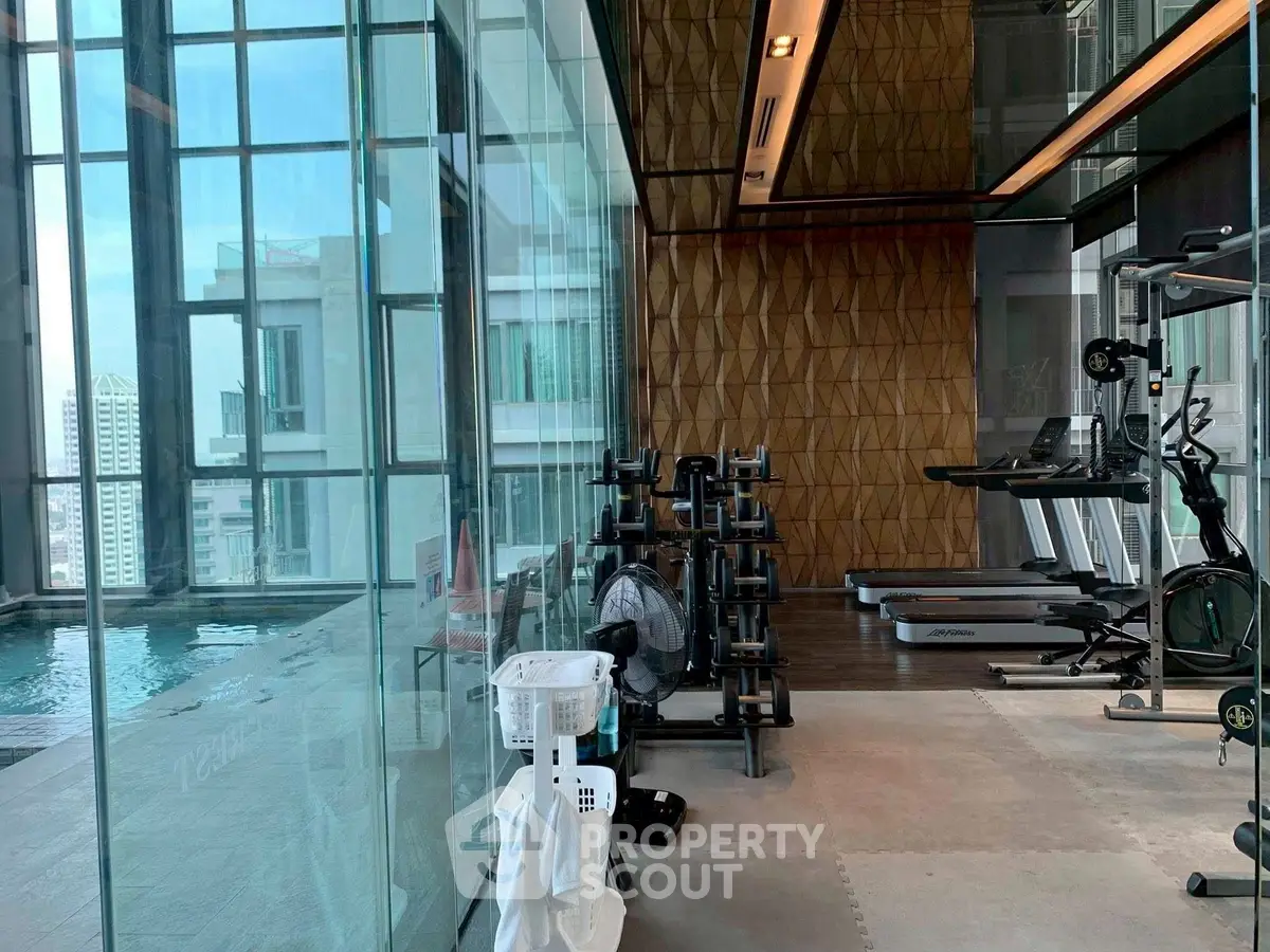 Luxurious gym with modern equipment and pool view in high-rise building