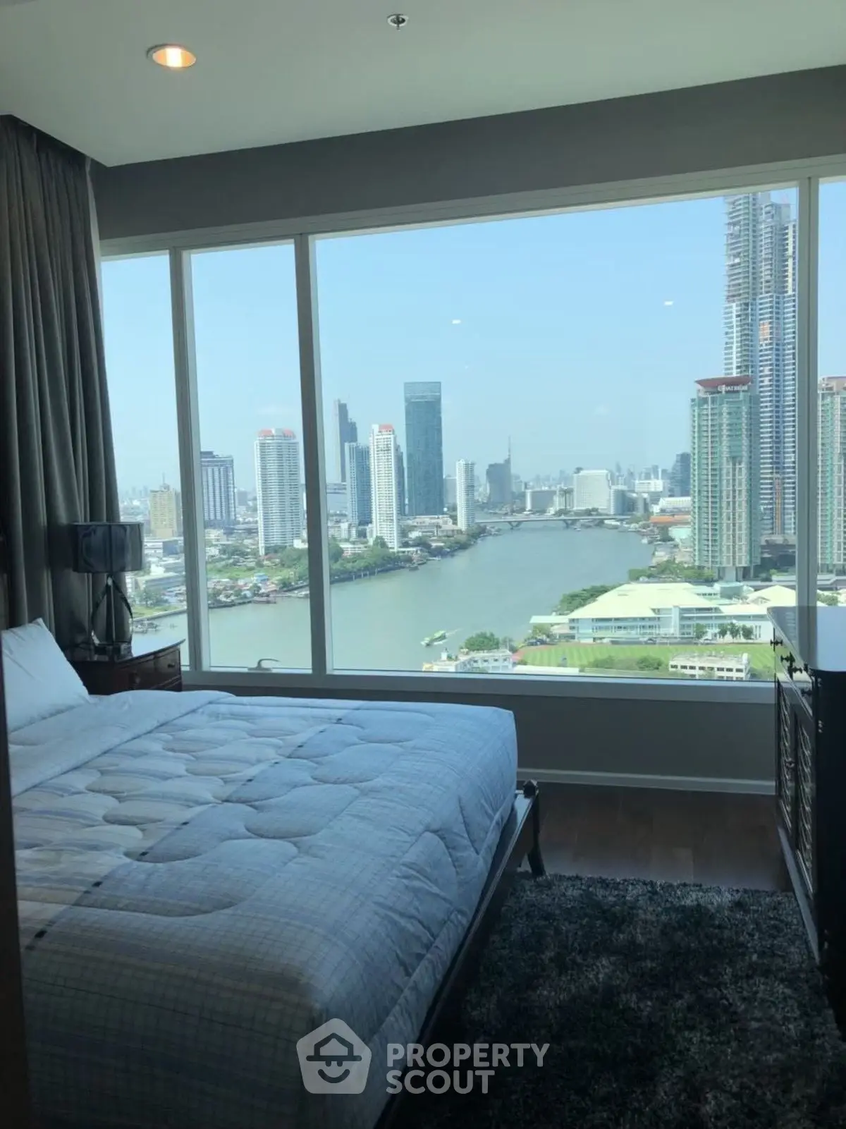 Luxurious bedroom with stunning city and river view from large window.