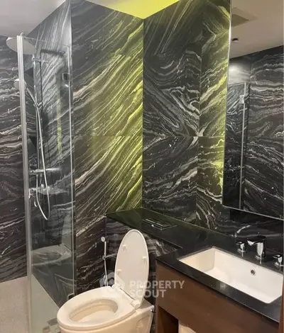 Luxurious modern bathroom with sleek black marble walls and glass shower enclosure.