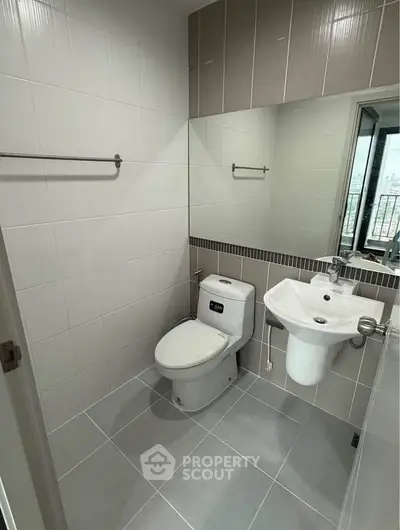 Modern bathroom with sleek fixtures and large mirror, perfect for contemporary living.