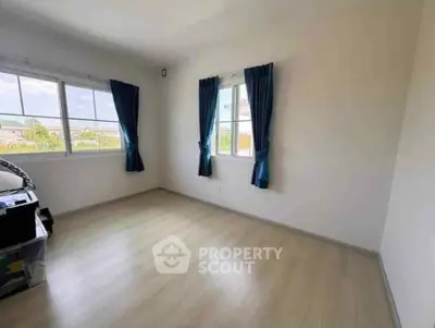 Spacious empty room with large windows and blue curtains, perfect for customization.
