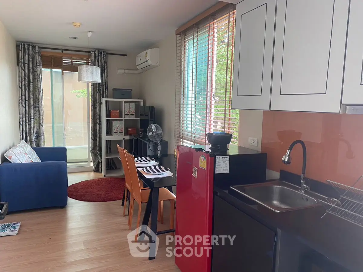 Modern open-layout living room with kitchen, featuring stylish furniture and natural light.