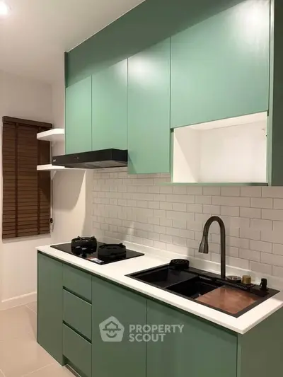 Modern kitchen with green cabinets and sleek appliances, featuring a minimalist design and efficient layout.