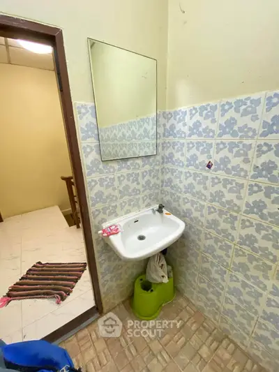 Compact bathroom with wall-mounted sink and floral tiles