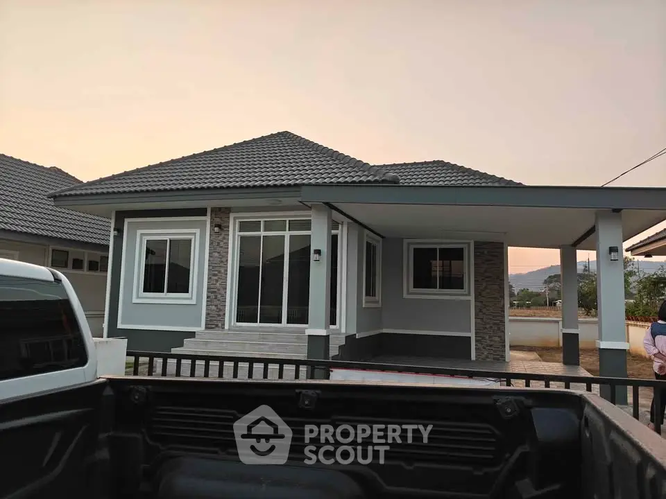 Charming single-story home with modern design and spacious driveway at sunset.