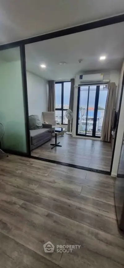 Modern living room with large windows and city view, featuring sleek flooring and contemporary furniture.