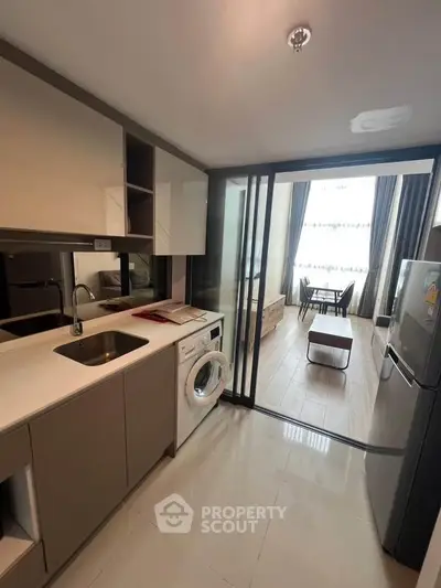 Modern kitchen with washing machine and open layout leading to a bright living area.