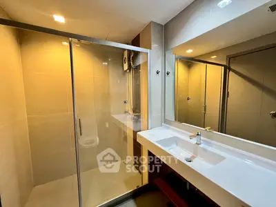 Modern bathroom with glass shower and sleek vanity in a contemporary apartment.