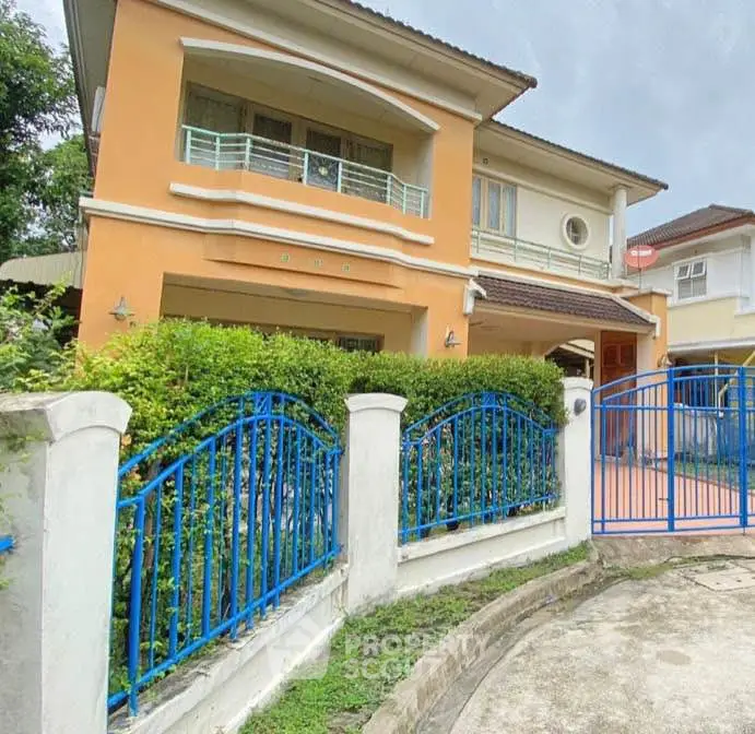 Charming two-story house with vibrant blue fencing and lush greenery, perfect for family living.