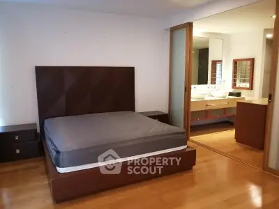 Spacious bedroom with ensuite bathroom and modern wooden furnishings.