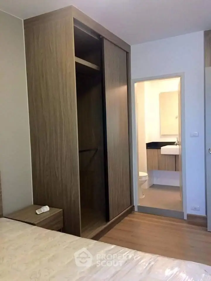 Modern bedroom with ensuite bathroom and wooden wardrobe in stylish apartment.