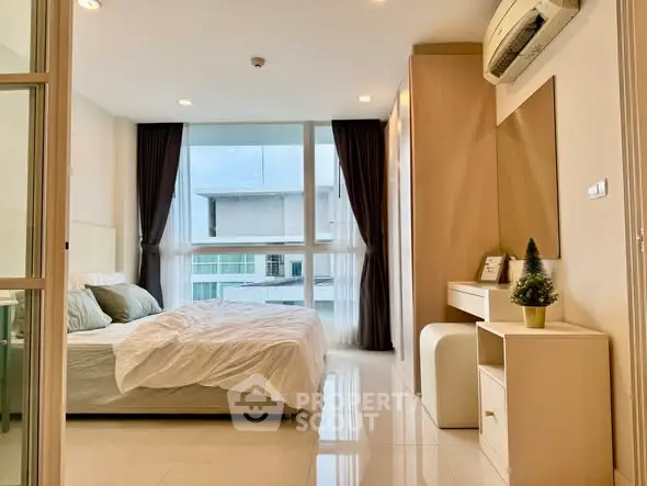 Modern bedroom with large window and stylish decor in a high-rise apartment.