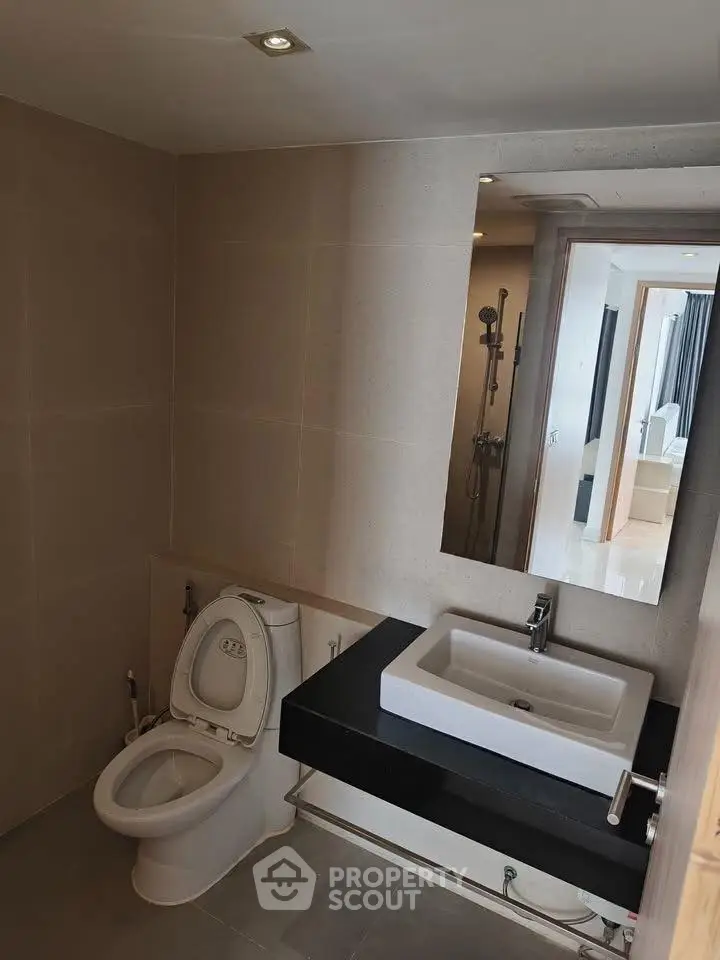 Modern bathroom with sleek fixtures and large mirror in contemporary apartment.