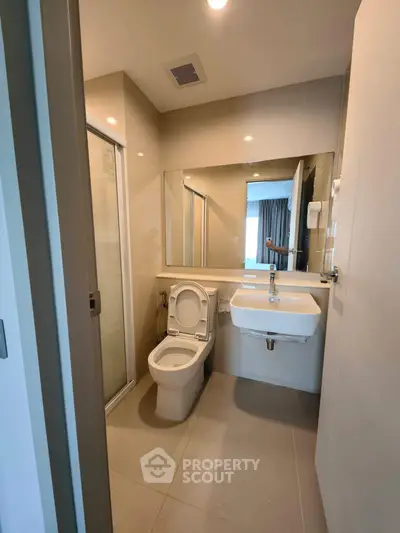 Modern bathroom with sleek fixtures and large mirror in contemporary apartment.