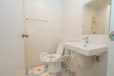 Modern bathroom with sleek white fixtures and stylish patterned floor tiles.