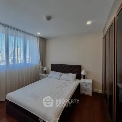 Spacious bedroom with elegant decor and city view, featuring a plush bed and ample natural light.