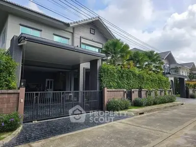 Modern two-story house with gated driveway and lush greenery