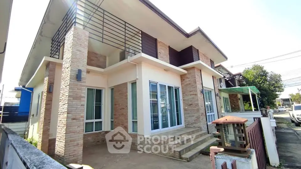 Modern two-story house with brick accents and large windows in a sunny neighborhood.