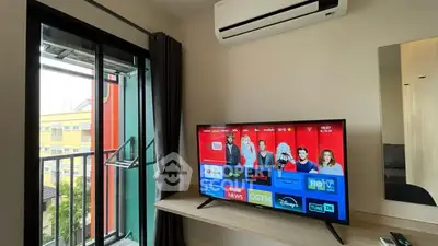 Modern living room with balcony, air conditioning, and smart TV setup.