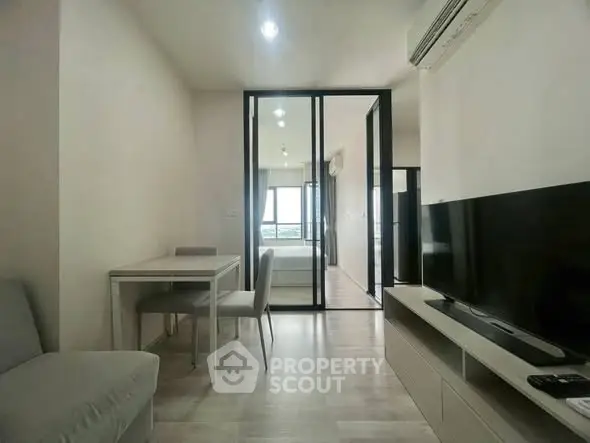 Modern living room with sleek furniture and glass partition leading to bedroom