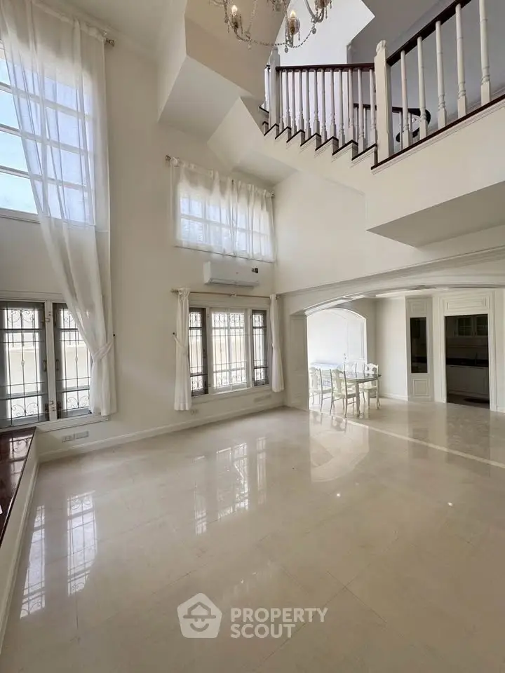 Spacious living room with high ceilings and elegant staircase
