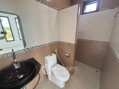 Modern bathroom with sleek black sink and tiled shower area.