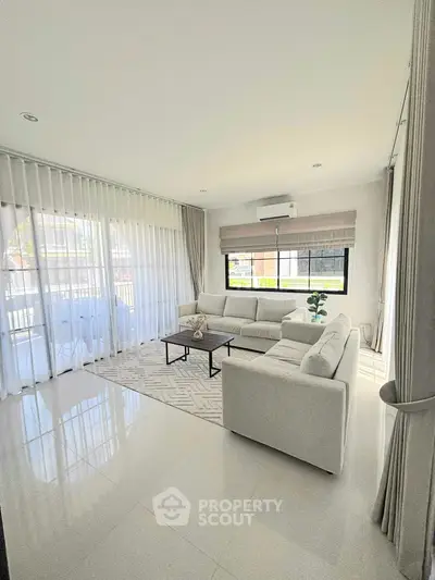 Bright modern living room with white sofas and large windows.