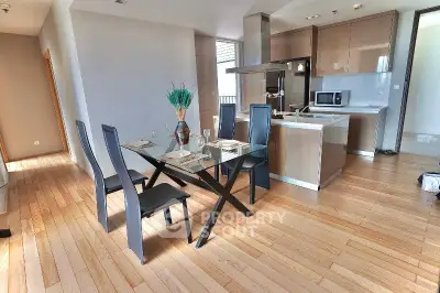 Modern open-layout kitchen and dining area with sleek glass table and stylish chairs.