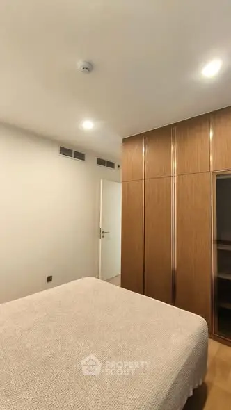 Modern bedroom with sleek wooden wardrobe and cozy bed