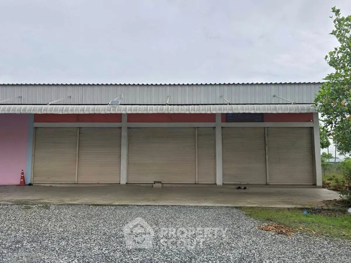 Commercial property with multiple shutter doors and ample parking space.