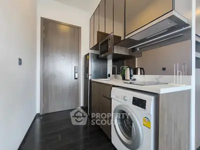 Modern kitchen with sleek appliances and washing machine in compact layout.
