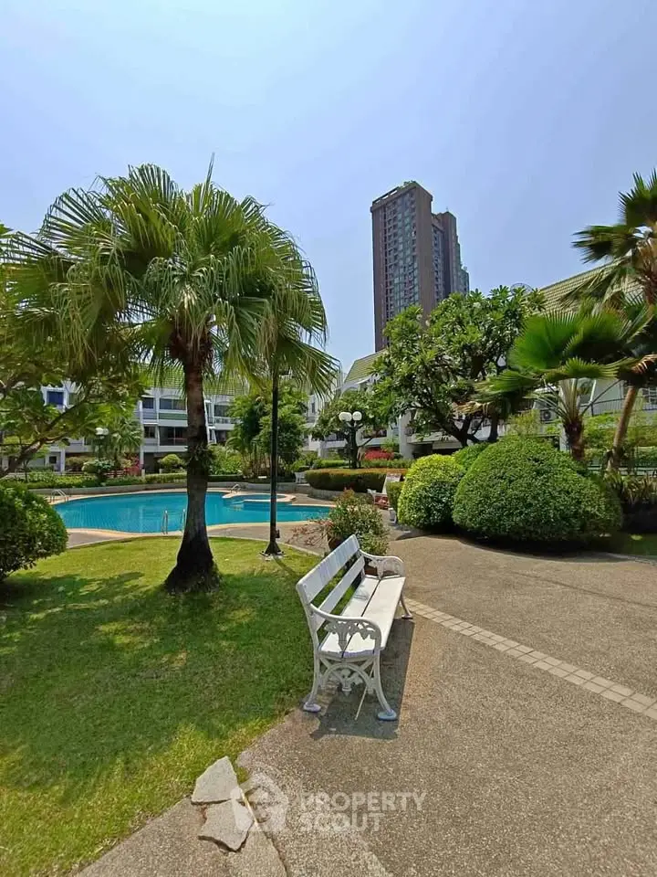 Lush garden with pool and high-rise building view, perfect for relaxation and urban living.