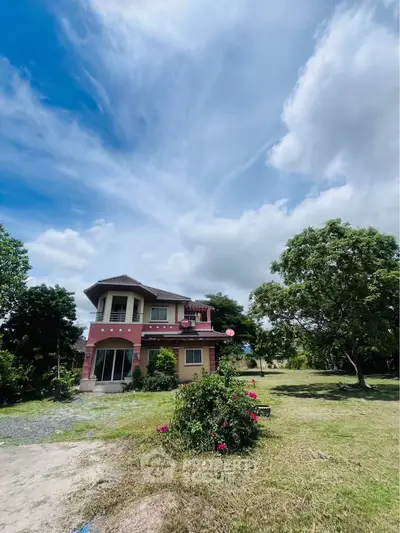 Charming two-story house with lush garden and clear blue sky, perfect for serene living.