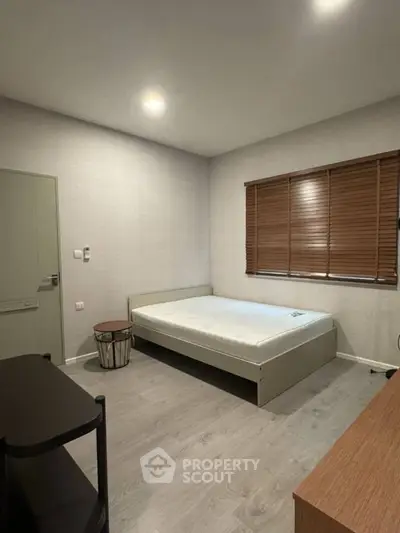 Minimalist bedroom with wooden blinds and modern furniture, perfect for a cozy retreat.