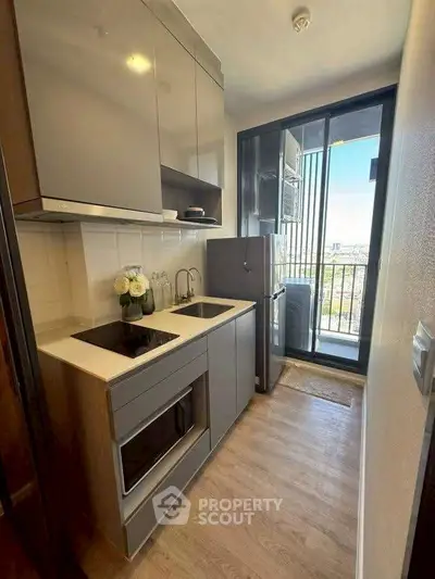 Modern kitchen with sleek cabinetry and balcony view, featuring built-in appliances and stylish design.